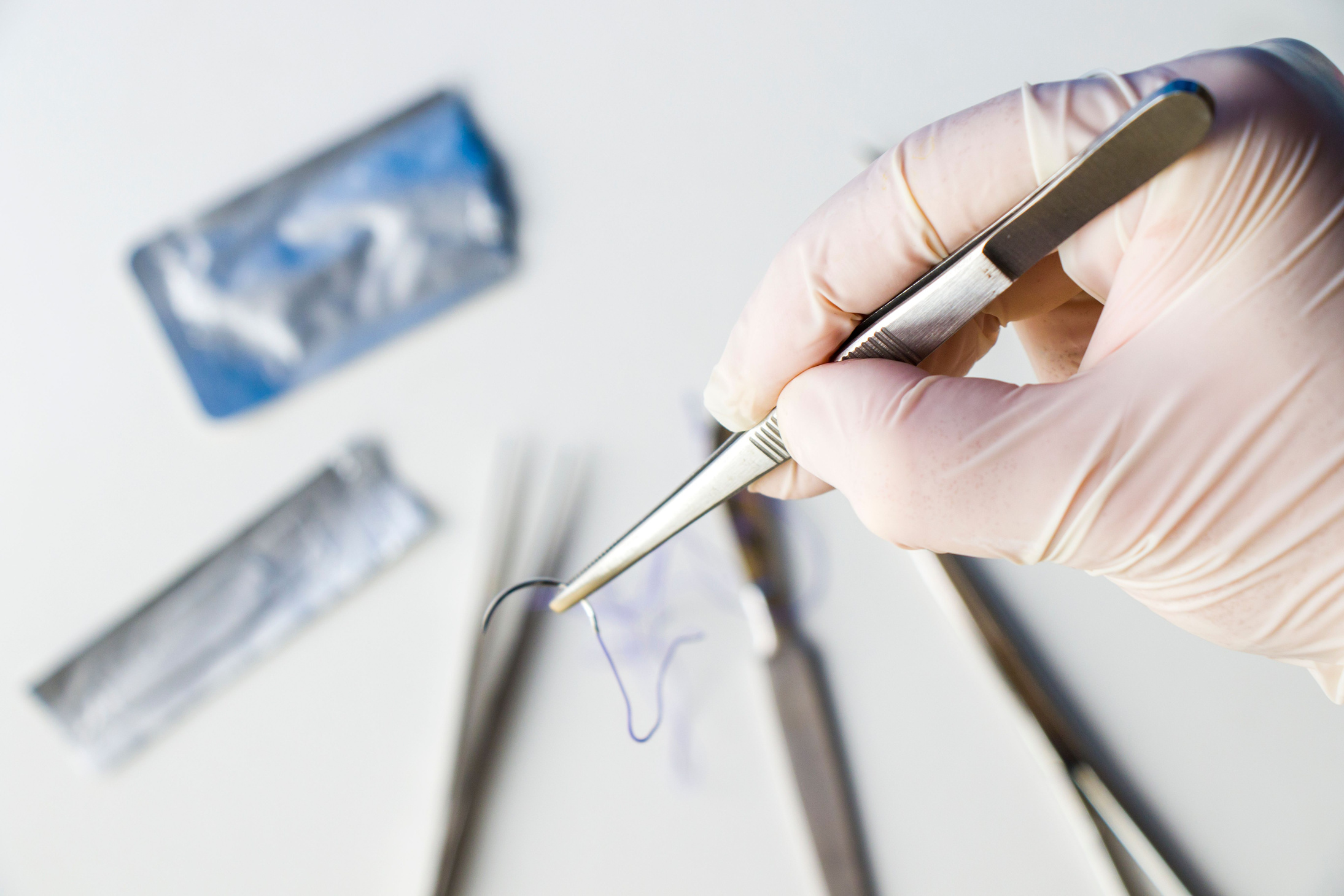 Doctor holding a suture with a surgical scalpel